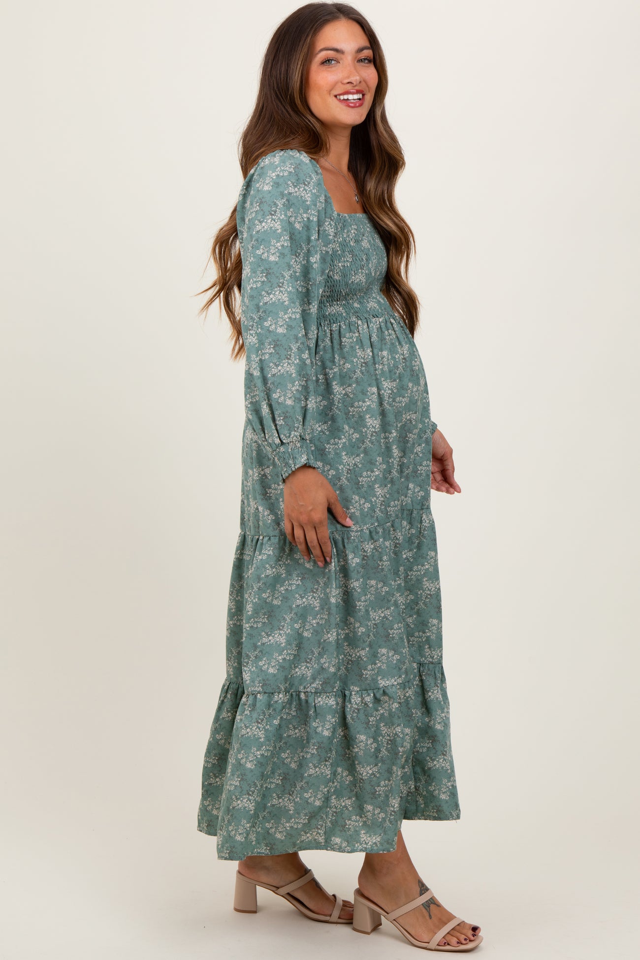 woman wearing a green floral maternity maxi dress with long sleeves and a baby bump visible