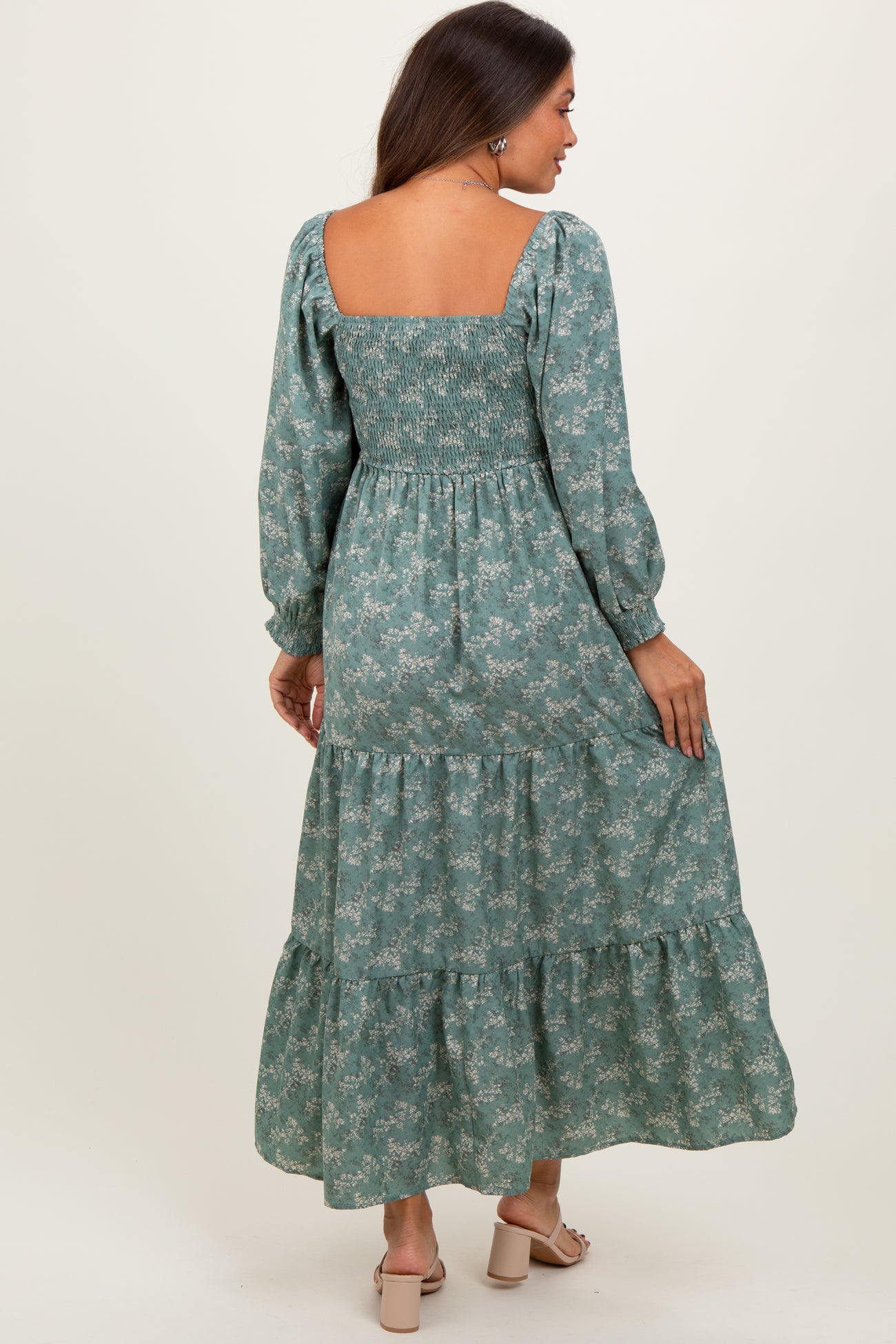 woman wearing a green floral maternity maxi dress with smocked bodice and puff sleeves, showing her baby bump