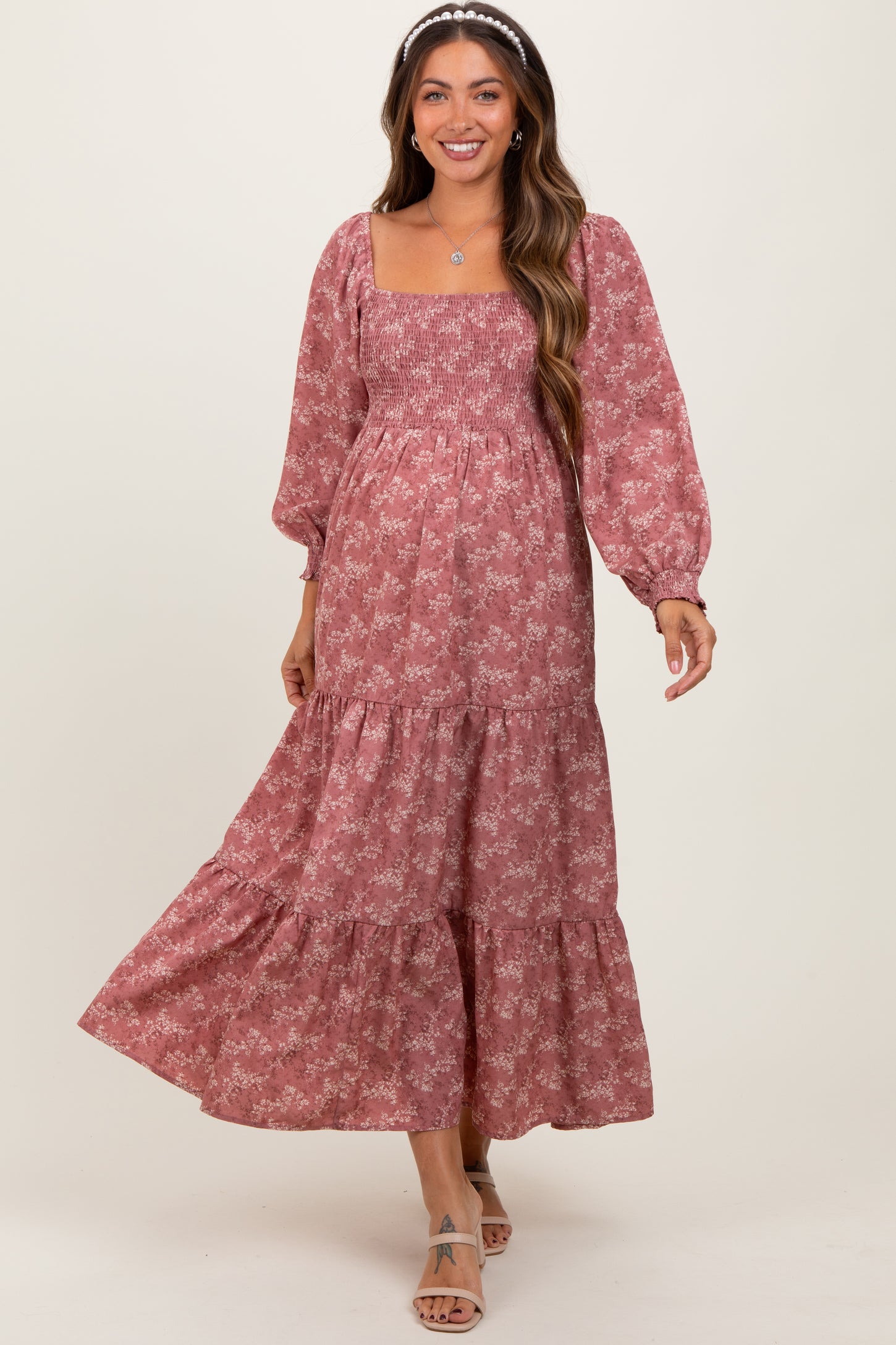woman wearing a pink floral maternity dress with long puff sleeves and a tiered skirt