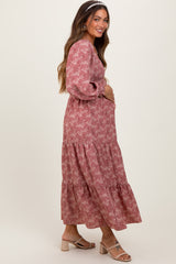 woman wearing a pink floral maternity maxi dress and holding her baby bump