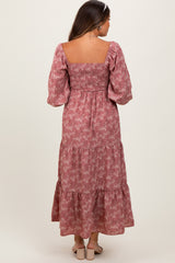 woman wearing a pink floral maternity maxi dress with puff sleeves and a smocked bodice, showing a baby bump