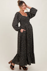woman wearing a black floral maternity maxi dress with smocked bodice and long puff sleeves, showing her baby bump