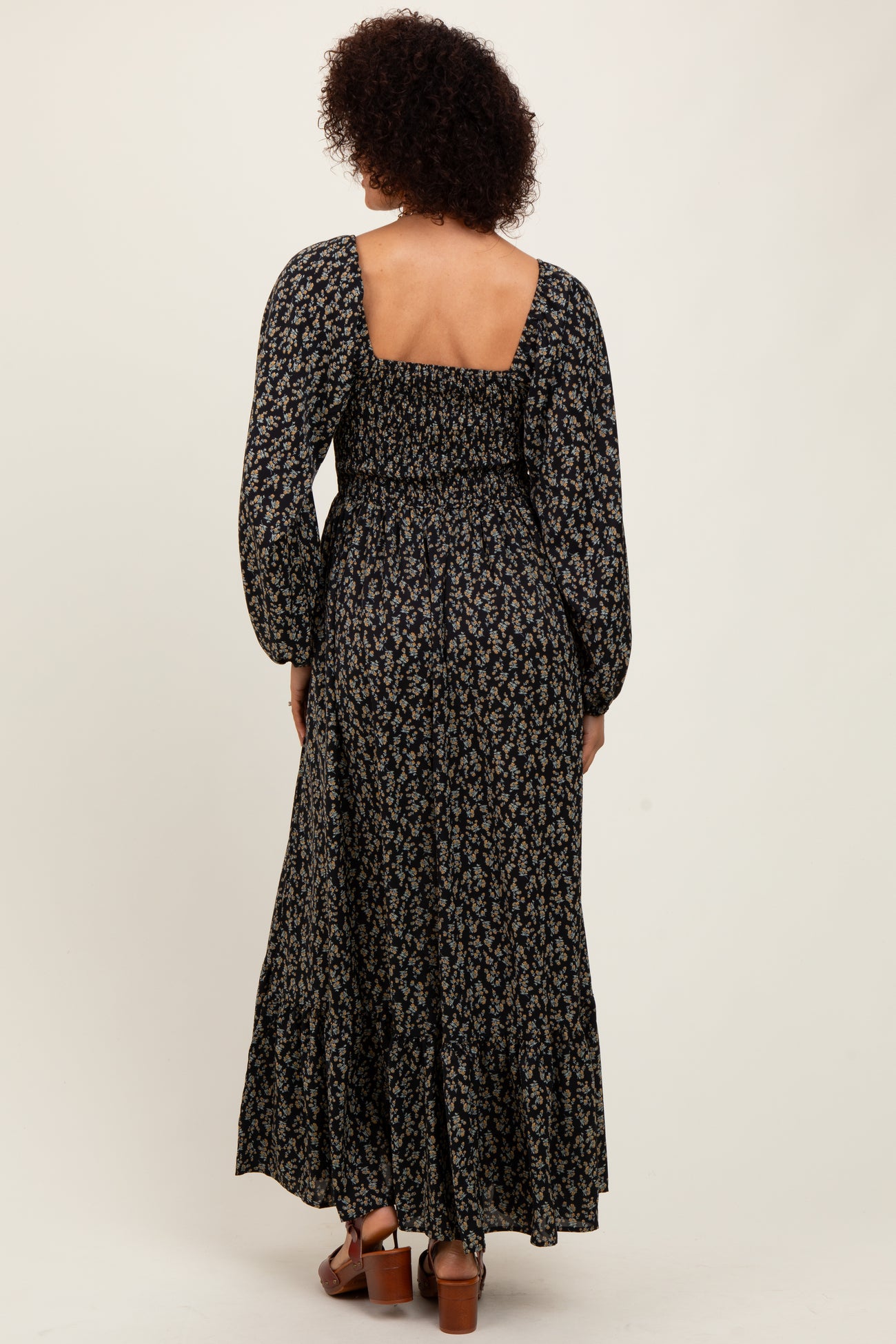 woman wearing a floral long sleeve maxi dress with a square back and tiered hem, viewed from the back