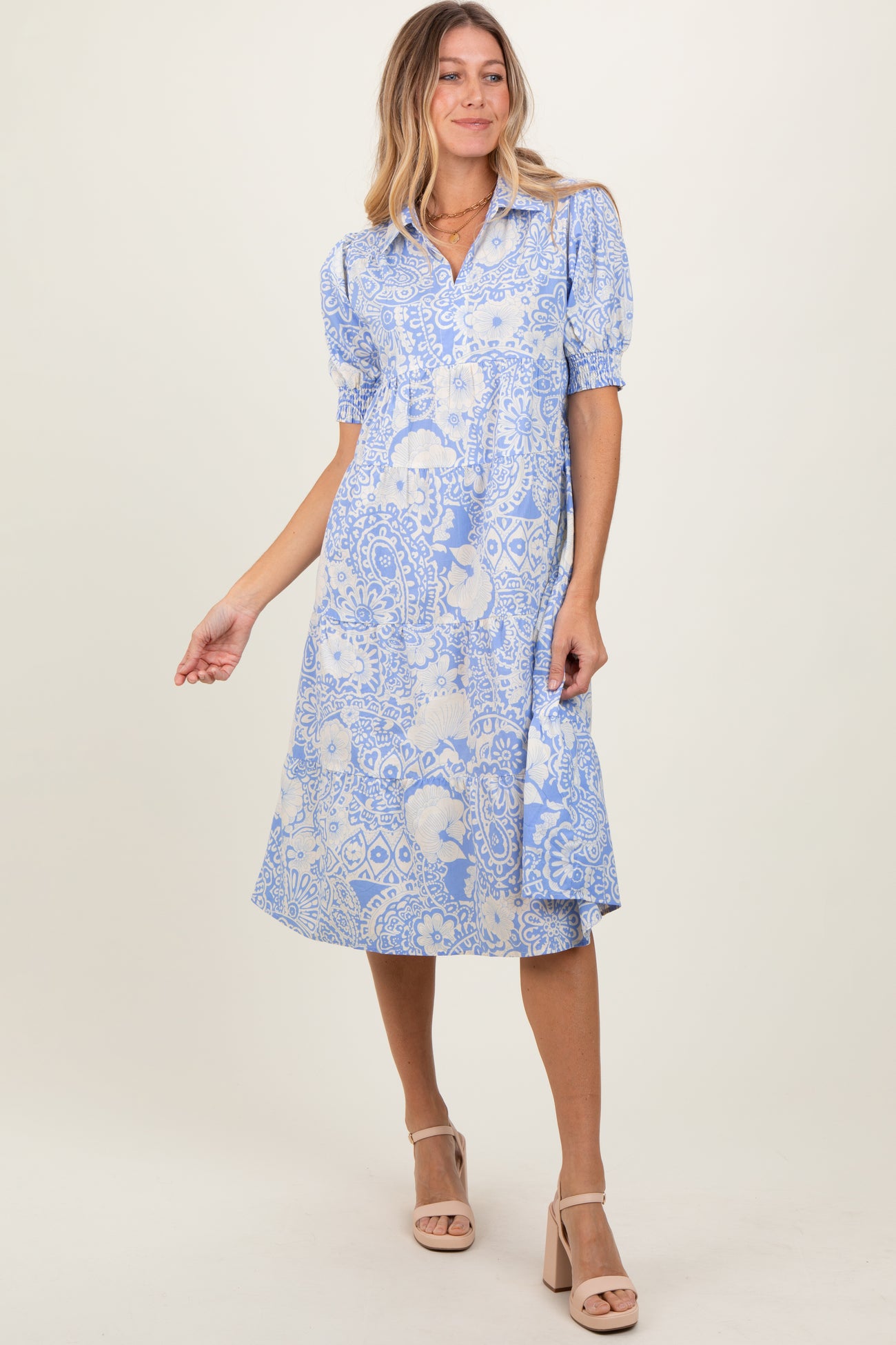 woman wearing a blue floral print midi dress with short puffed sleeves and a button-down front