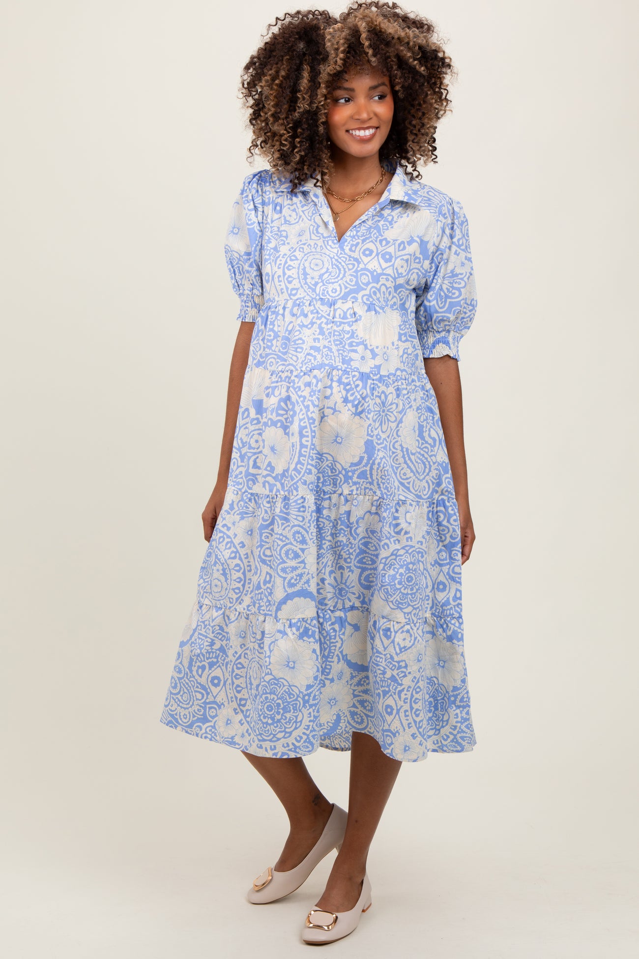 woman wearing a blue patterned maternity dress with puff sleeves and a flowy skirt, showing her baby bump