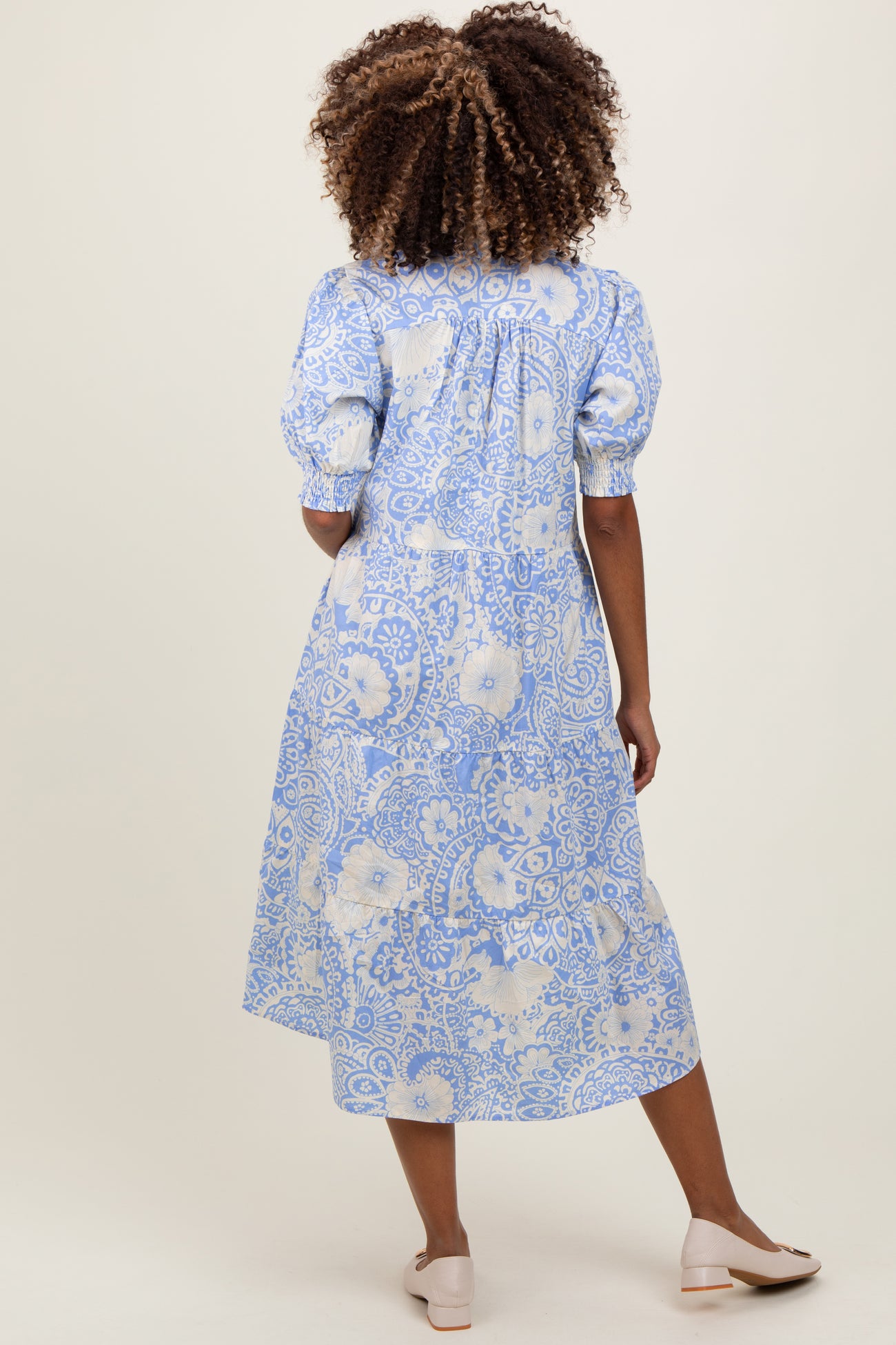 woman wearing a blue and white floral print maternity dress with puff sleeves and a tiered skirt