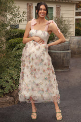 woman wearing a floral maternity dress with smocked bodice and pink shoulder ties, showing her baby bump