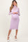 woman wearing a lavender maternity dress with long sleeves and a fitted silhouette, showing her baby bump