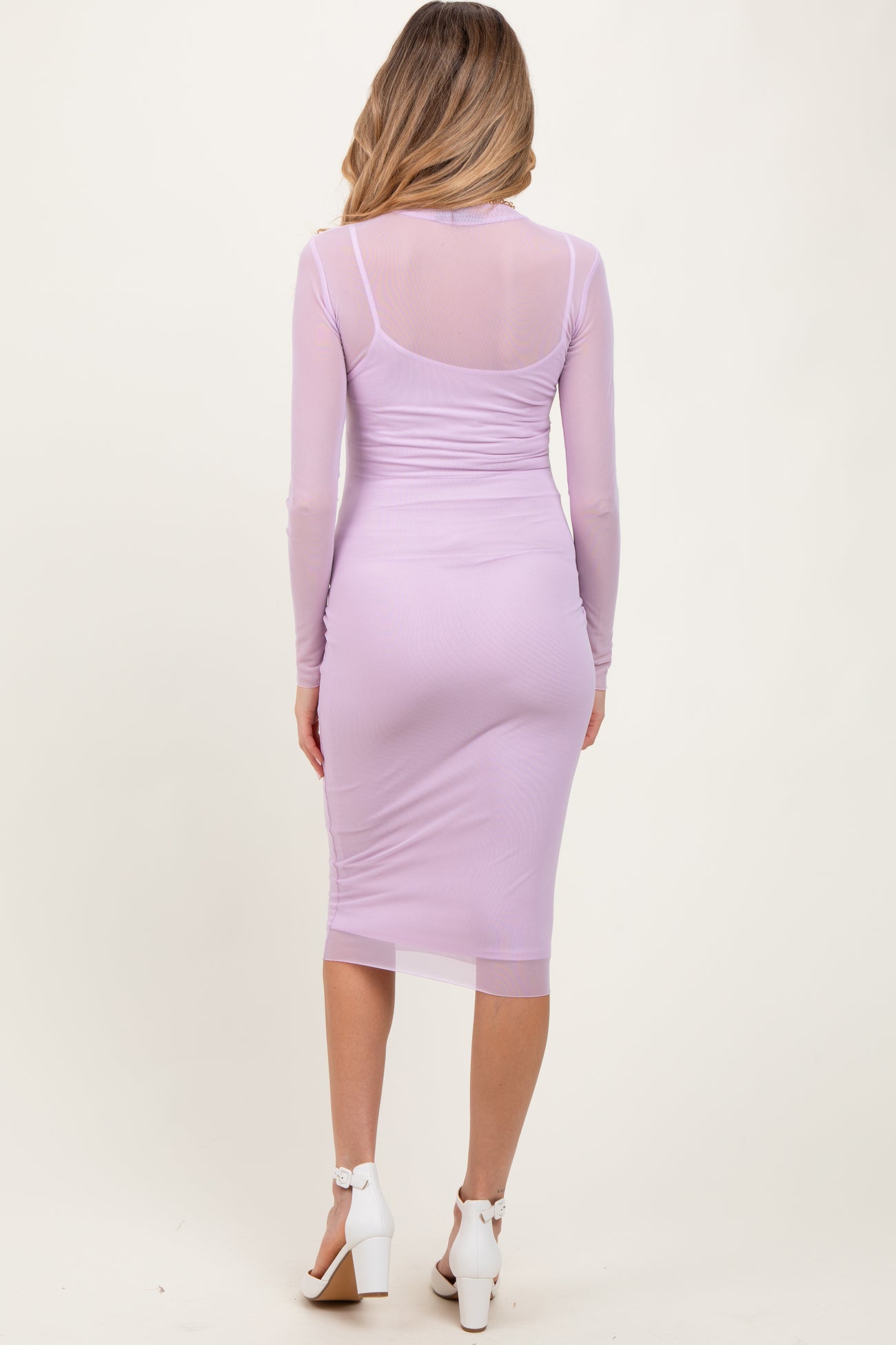 woman wearing a light purple long sleeve maternity dress with a fitted silhouette and sheer back details