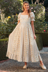 woman wearing a floral print maternity dress with short puff sleeves and a flowing skirt, standing outdoors with a baby bump