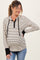 woman wearing a cream and black striped maternity hoodie with a button-up neckline and black cuffs, showing her baby bump