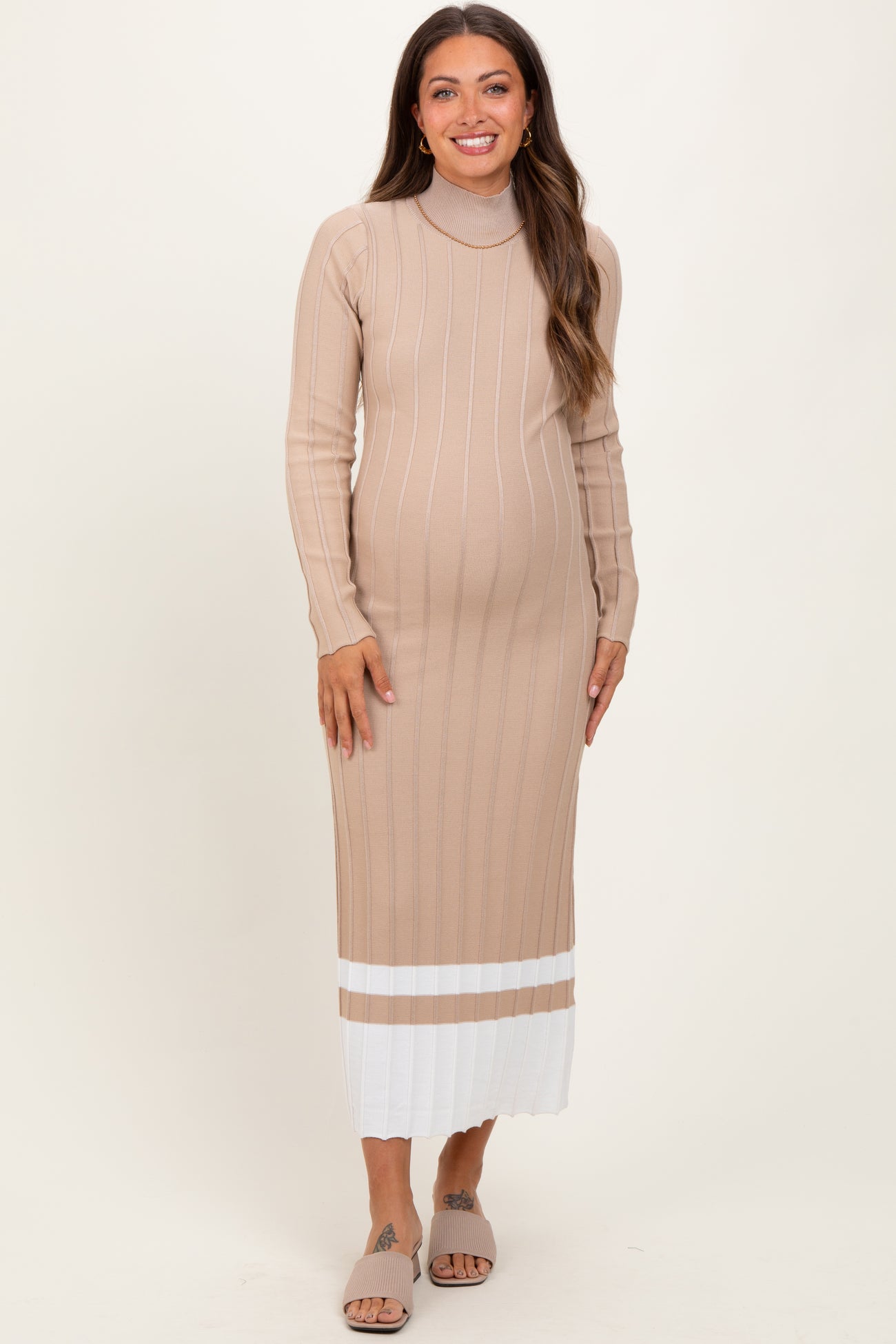 woman wearing a beige maternity dress with long sleeves and a ribbed texture, showing her baby bump