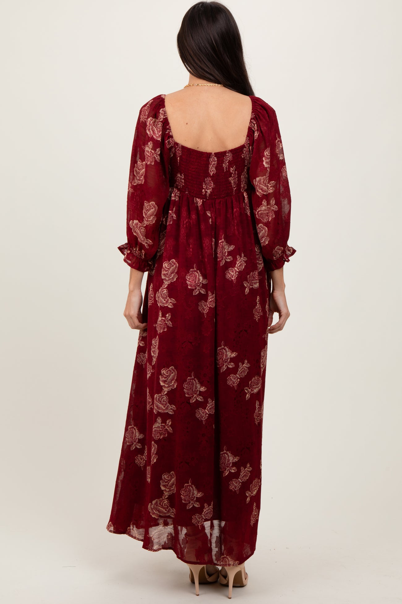 woman wearing a burgundy floral maxi dress with long sleeves and a smocked back detail