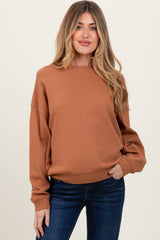woman wearing a rust brown oversized maternity sweatshirt with long sleeves and a round neckline