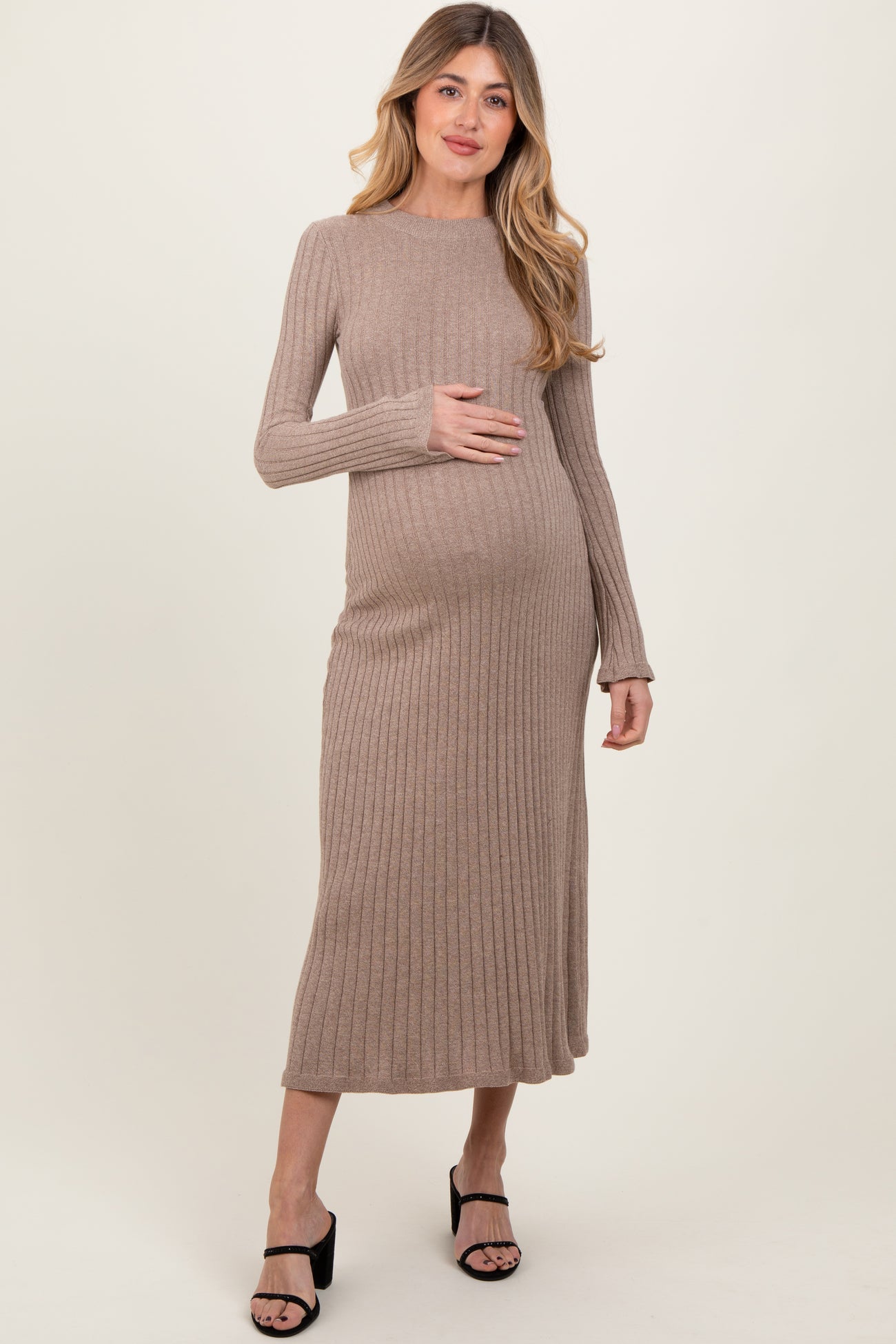 woman wearing a beige ribbed maternity dress and holding her baby bump
