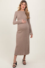 woman wearing a beige ribbed maternity dress and holding her baby bump
