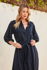 woman wearing a navy blue button-up shirt dress with a tie waist and balloon sleeves