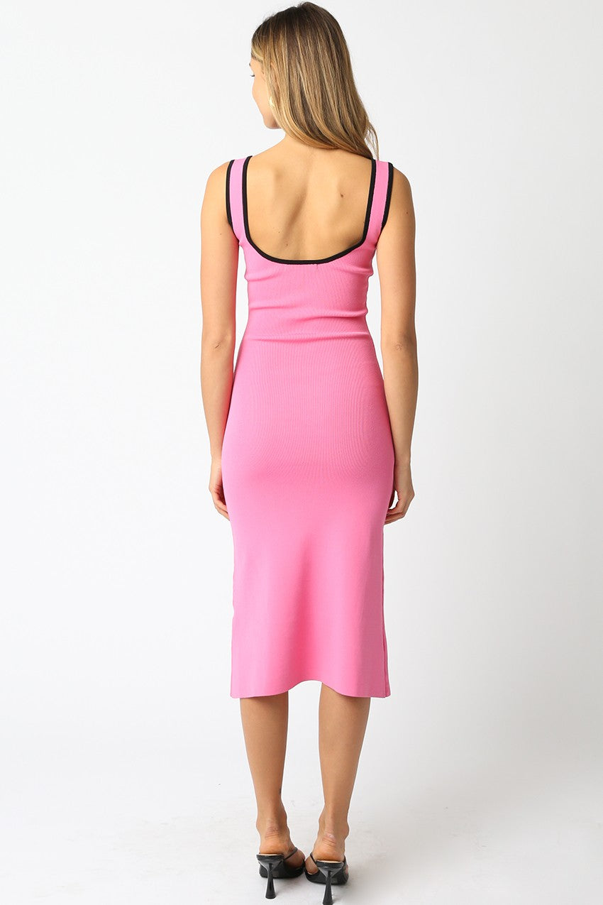 woman wearing a fitted pink midi dress with black strap detailing, showing a bare back