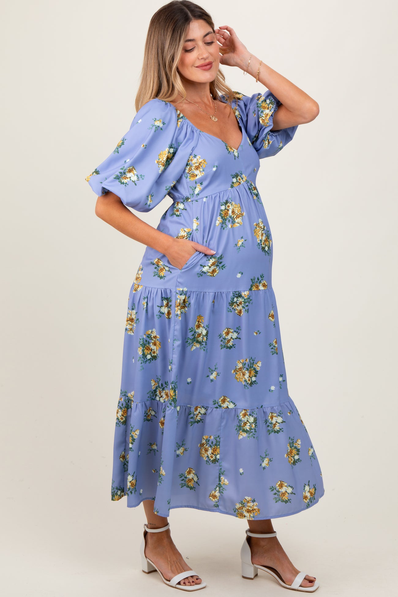 woman wearing a lavender floral maternity dress with short puff sleeves and a tiered skirt, showcasing her baby bump