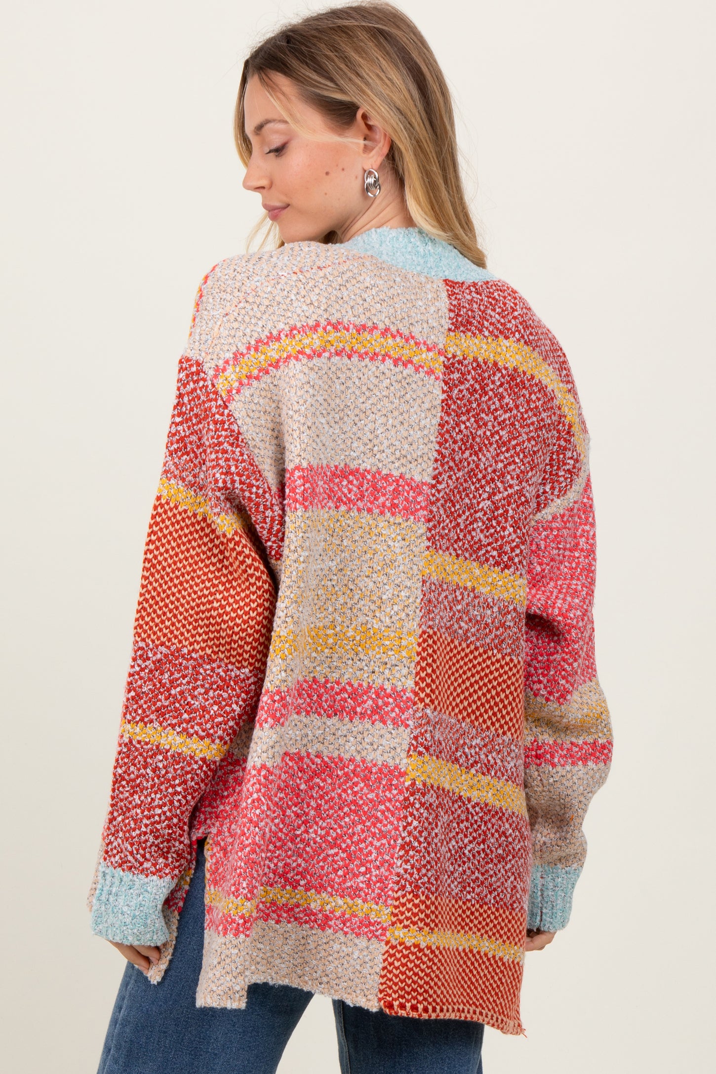 woman wearing a multicolored oversized knit cardigan with a patchwork design, showing the back view
