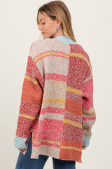 woman wearing a multicolored oversized knit cardigan with a patchwork design, showing the back view