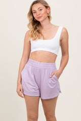 woman wearing a white crop top and lavender high-waisted shorts with side pockets