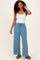 woman wearing a white tank top and blue wide leg lounge pants with side pockets