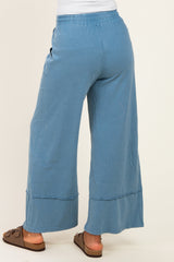 woman wearing blue wide leg pants with an elastic waistband and side pockets, shown from the back