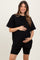 woman wearing a black oversized maternity t-shirt and black biker shorts, holding her baby bump
