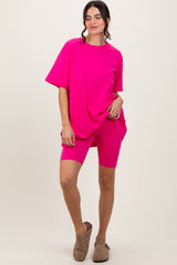 woman wearing a bright pink oversized t-shirt and matching biker shorts, standing with one hand on hip