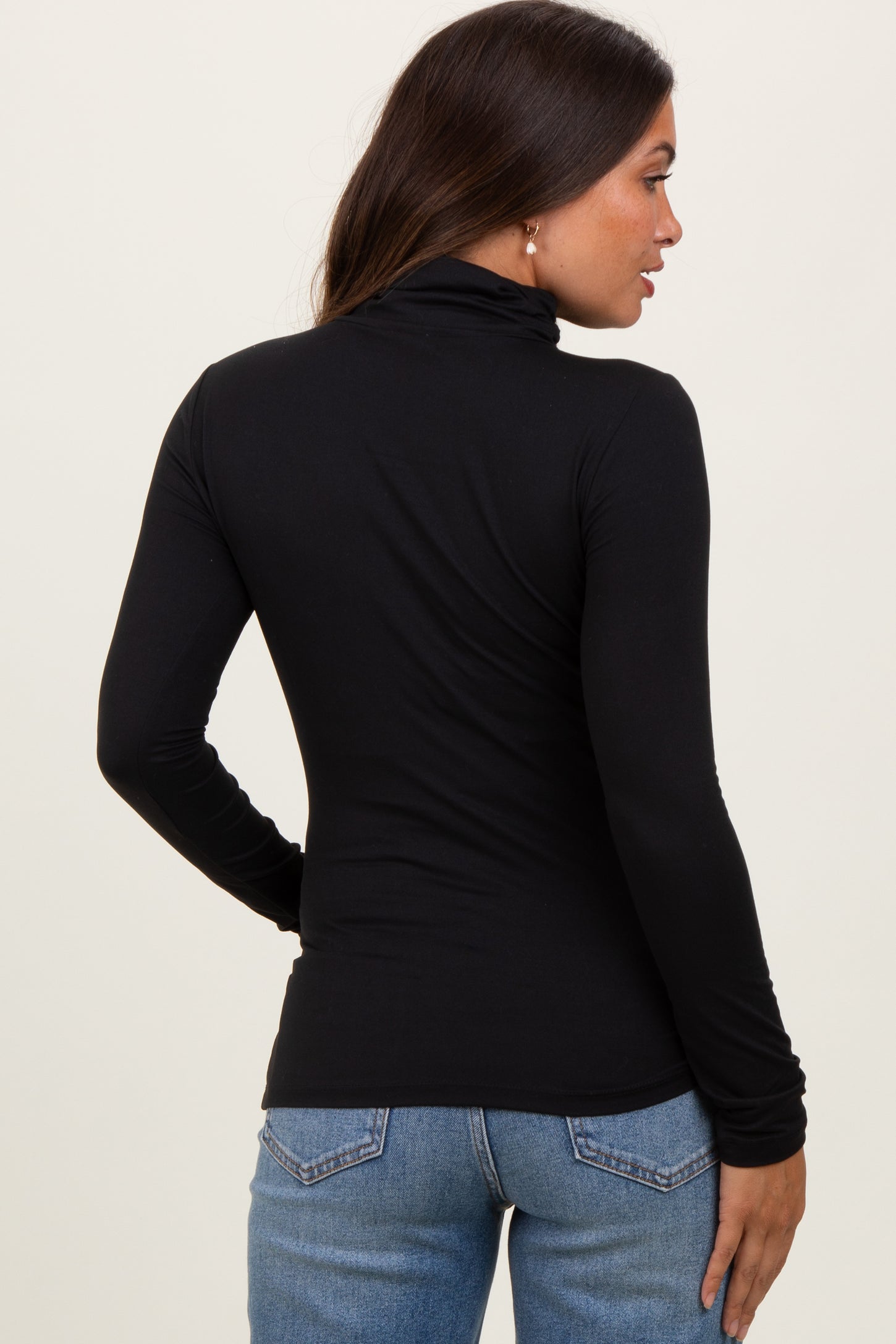 woman wearing a black long sleeve maternity top with a mock neck and fitted silhouette