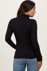 woman wearing a black long sleeve maternity top with a mock neck and fitted silhouette