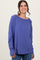 woman wearing a purple long sleeve top with a relaxed fit and round neckline, smiling at the camera