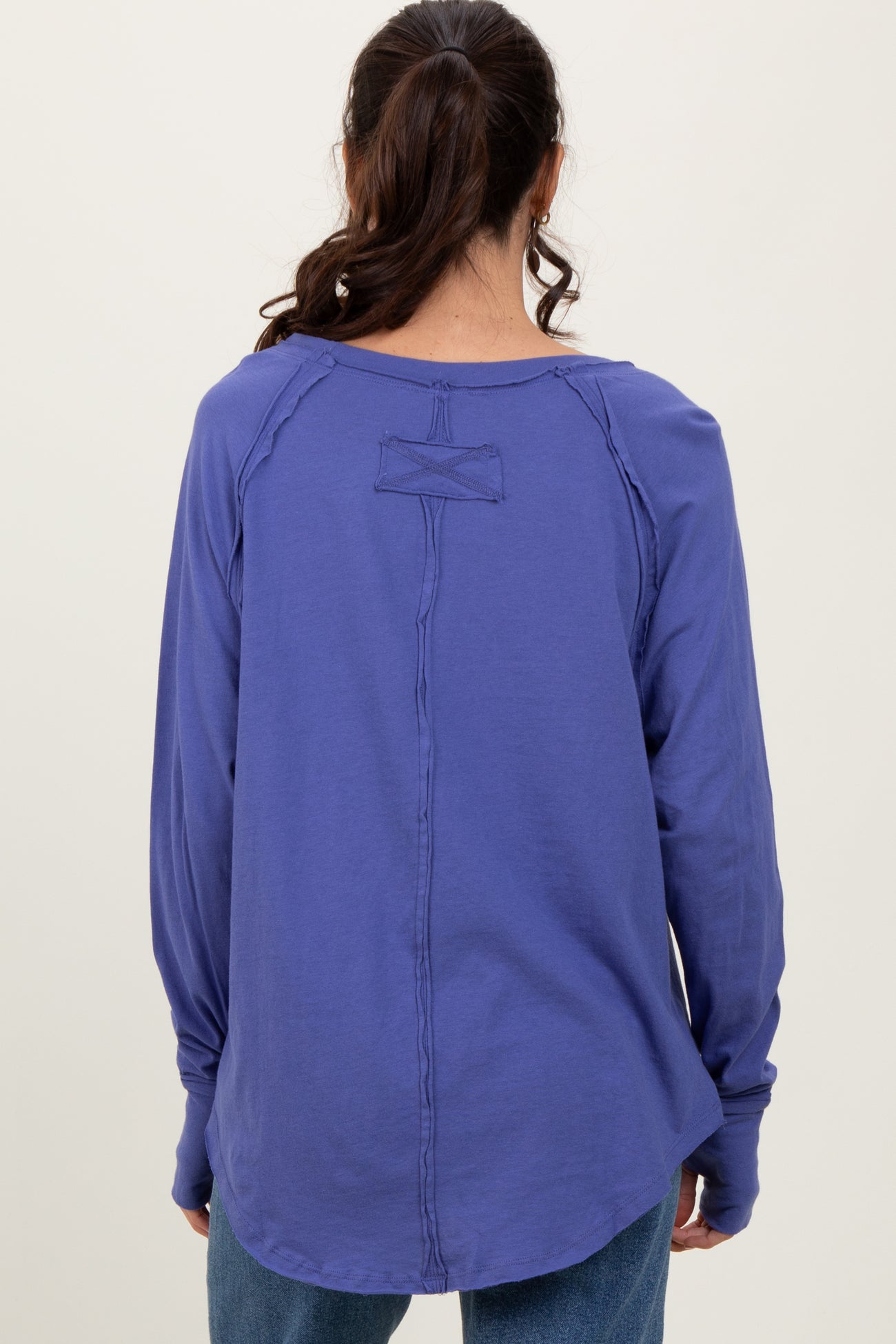 woman wearing a purple long sleeve shirt with a unique back detail and relaxed fit