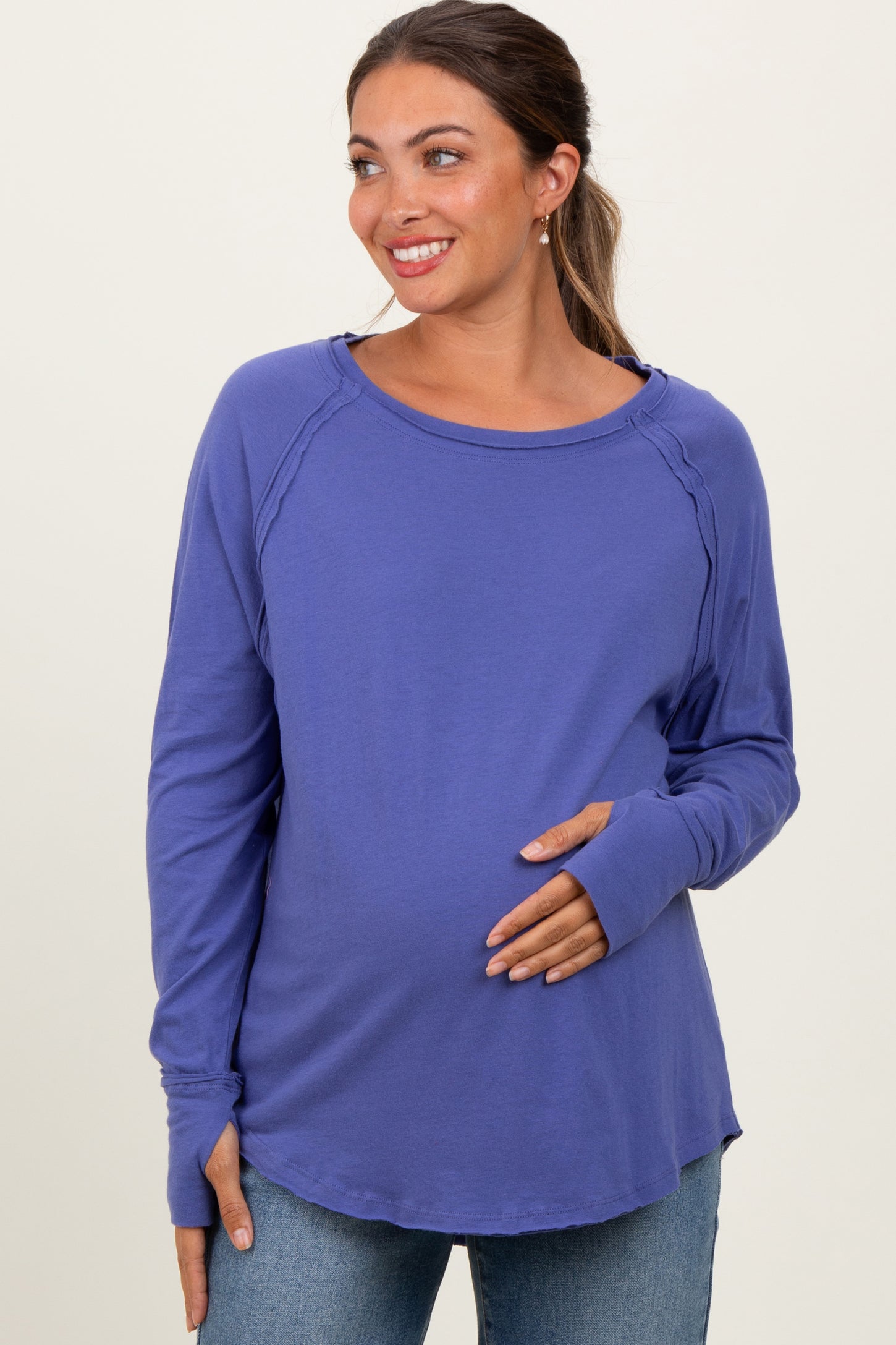 woman wearing a purple long sleeve maternity top and holding her baby bump