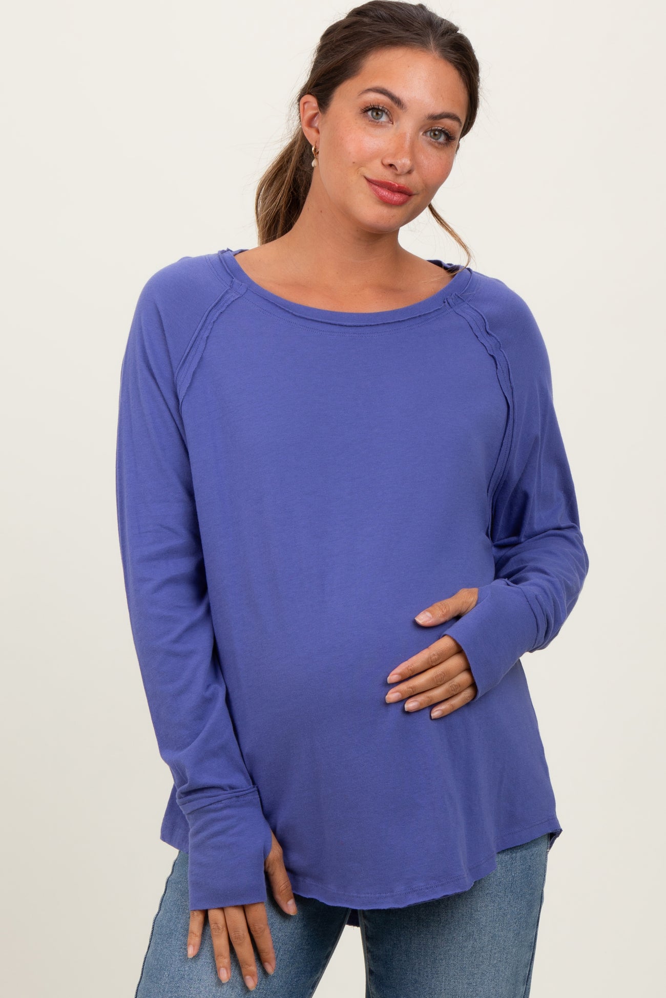 woman wearing a purple long sleeve maternity top with a relaxed fit and holding her baby bump