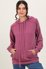 woman wearing a light pink ribbed hoodie with a front pocket and drawstring, styled with blue jeans