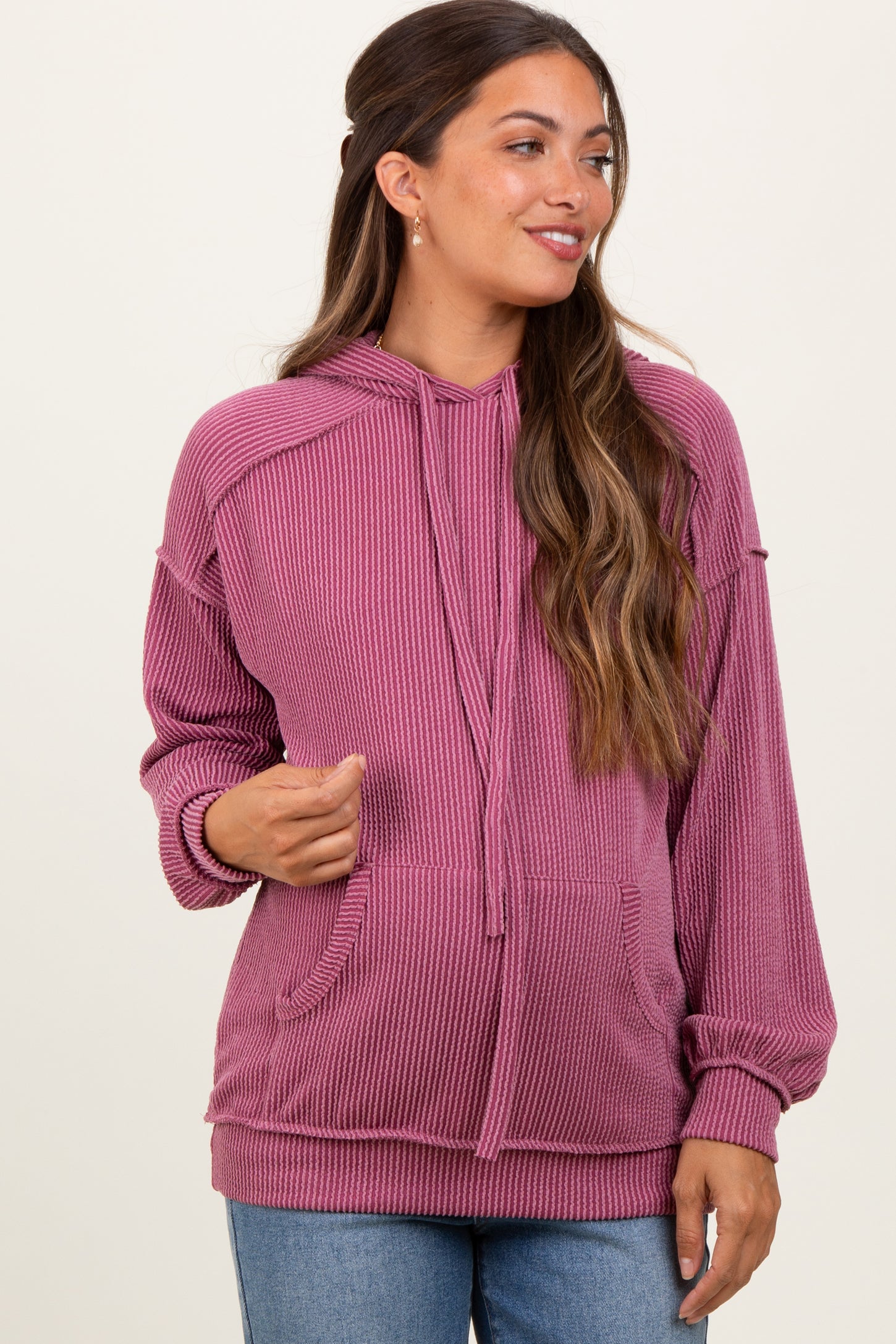 woman wearing a pink ribbed maternity hoodie with a drawstring and front pockets