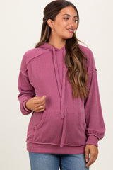 woman wearing a pink ribbed maternity hoodie with a drawstring and front pockets