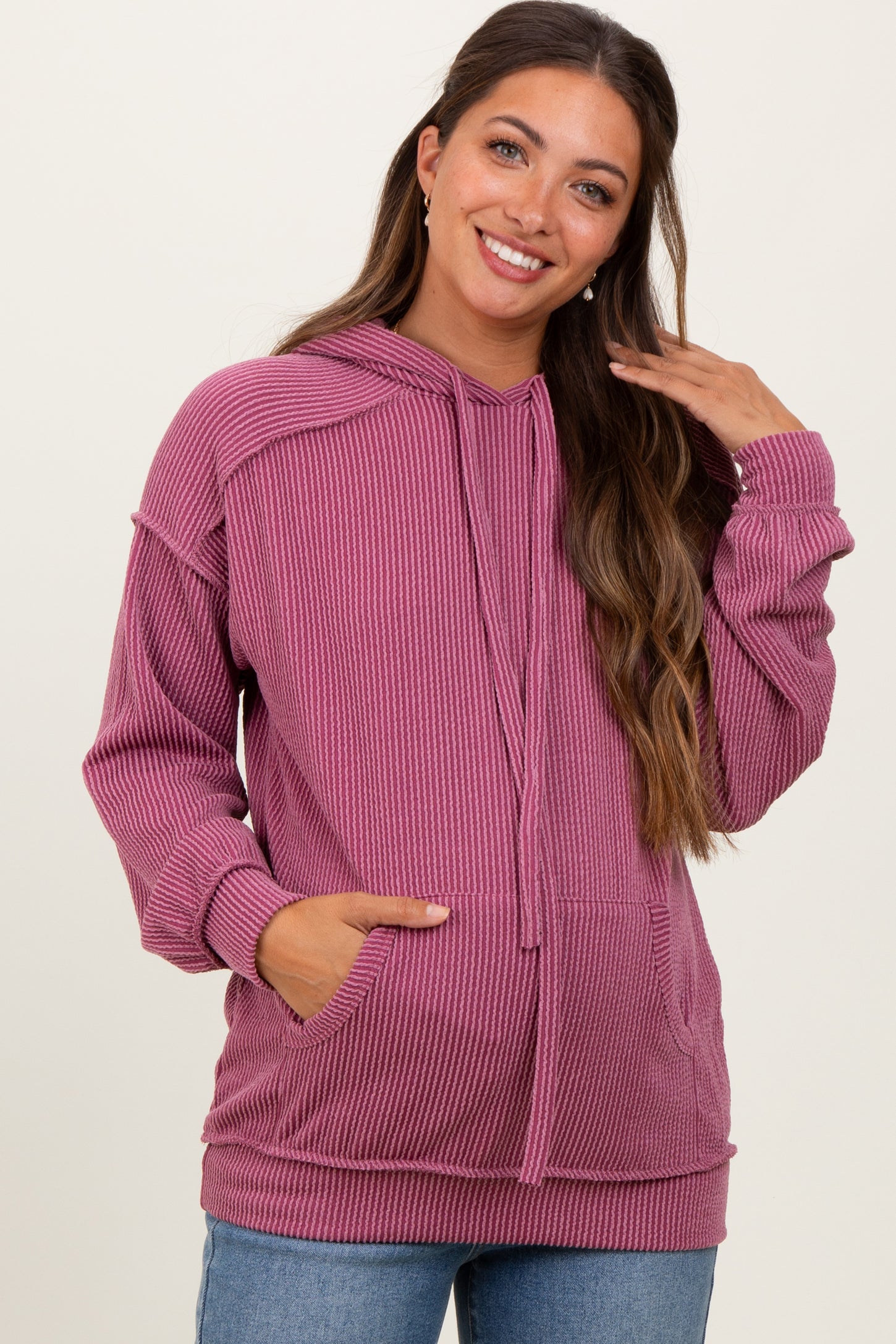 woman wearing a raspberry ribbed maternity hoodie with a kangaroo pocket and drawstring hood