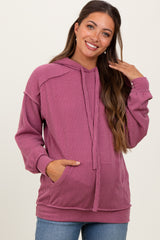 woman wearing a raspberry ribbed maternity hoodie with a kangaroo pocket and drawstring hood