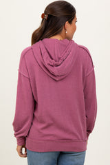 woman wearing a pink ribbed maternity hoodie with a drawstring hood and a relaxed fit, showing a baby bump from the back