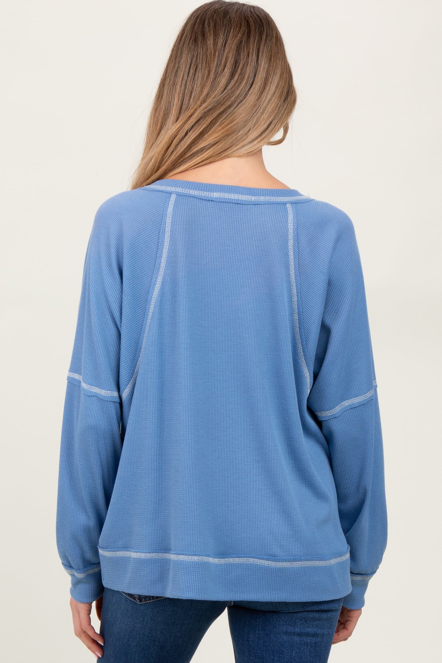 woman wearing a light blue maternity sweatshirt with a relaxed fit and long sleeves, viewed from the back