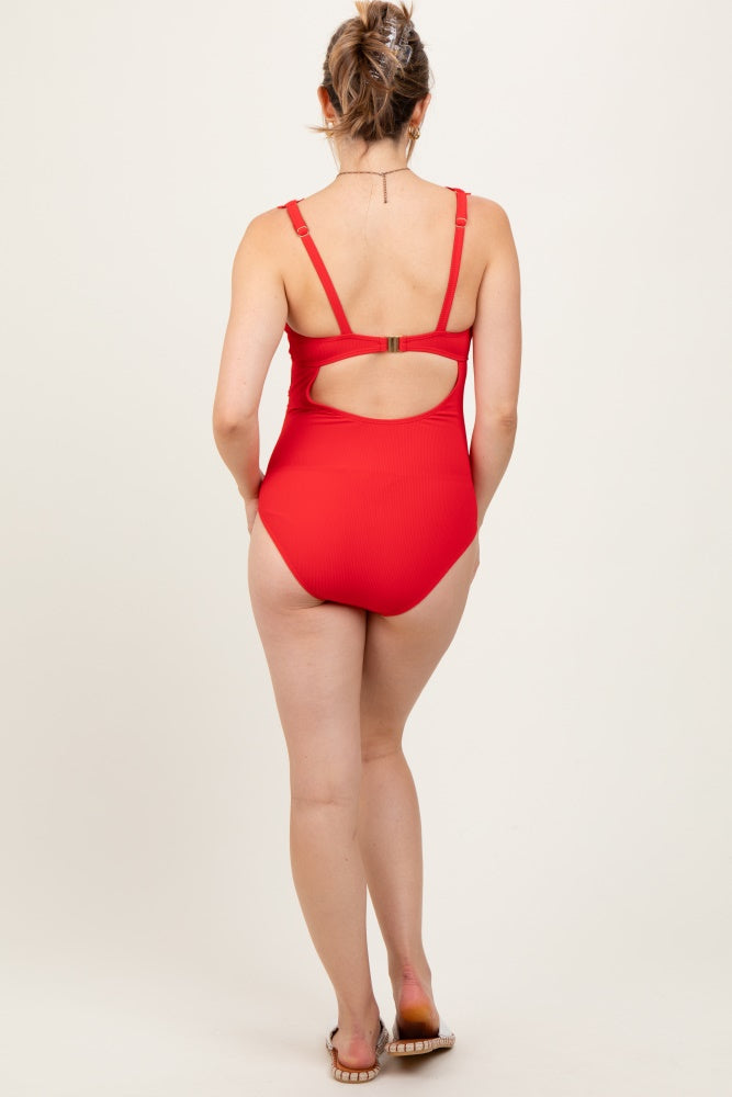 woman wearing a red maternity swimsuit with a cutout back, showing her pregnant baby bump from the back