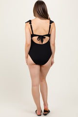 woman wearing a black ribbed maternity swimsuit with adjustable tie straps and open back design