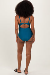 woman wearing a teal one-piece swimsuit with a cutout back and thin straps