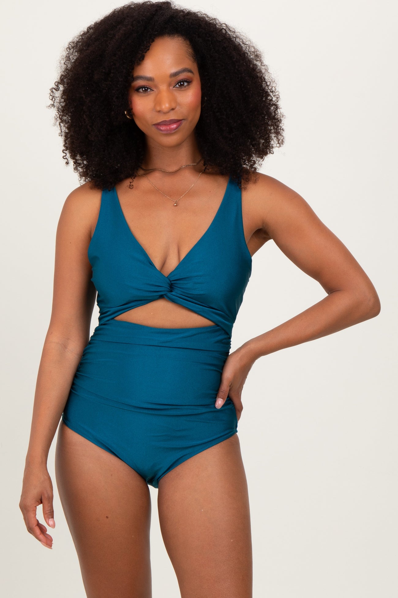 woman wearing a teal cutout one-piece swimsuit with a twist detail and high waist design