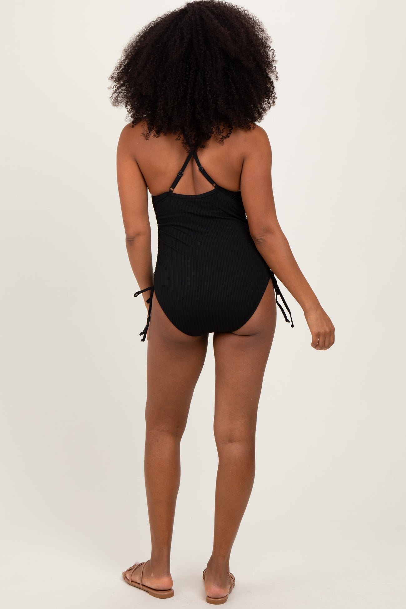 woman wearing a black one-piece swimsuit with adjustable side ties and crisscross back details