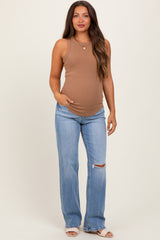 woman wearing a brown sleeveless maternity top and distressed light blue jeans with a visible baby bump