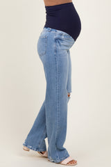 woman wearing light blue maternity flared jeans and a navy top, showing her baby bump